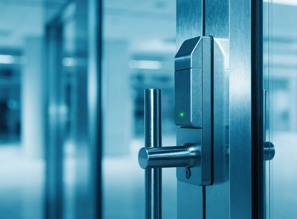 Technician fitting a commercial lock and access control reader to an office door