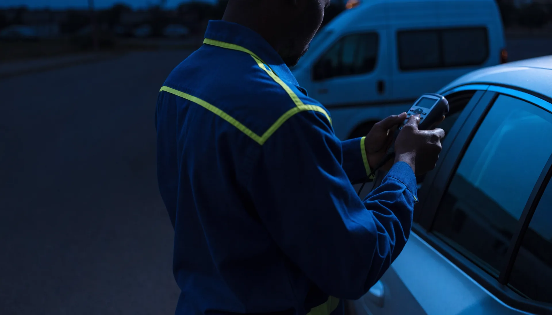 TK Lock & Key Locksmith technician programming a car key at the roadside beside the service van